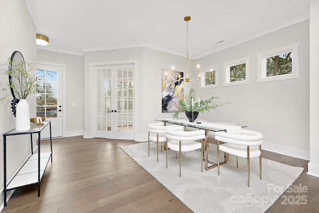 dining area with french doors, ornamental molding, dark wood-type flooring, and a notable chandelier