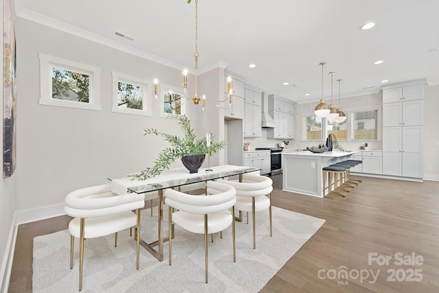 dining room featuring crown molding, a chandelier, and light wood-type flooring