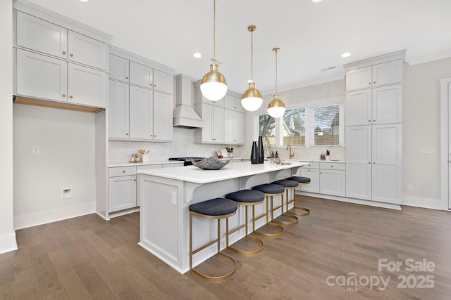 kitchen with a kitchen island, decorative light fixtures, a breakfast bar area, dark hardwood / wood-style flooring, and custom range hood