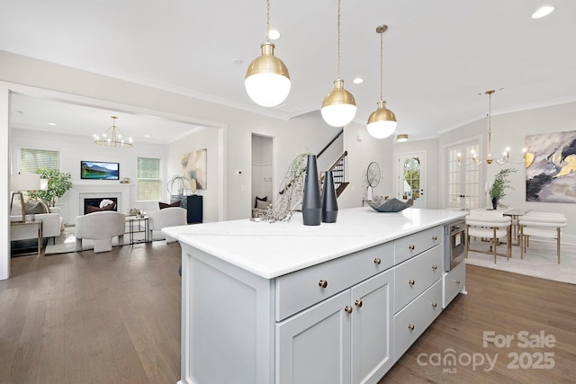 kitchen featuring an inviting chandelier, hanging light fixtures, dark hardwood / wood-style flooring, a kitchen island, and light stone countertops