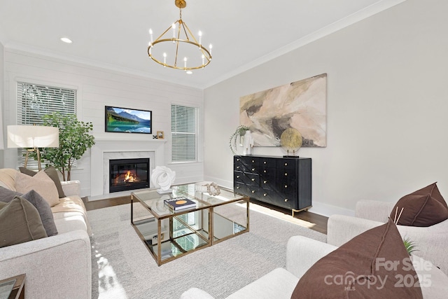 living room with crown molding, a high end fireplace, hardwood / wood-style floors, and a notable chandelier