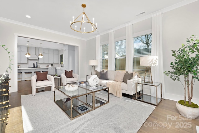 living room featuring hardwood / wood-style flooring, ornamental molding, and an inviting chandelier