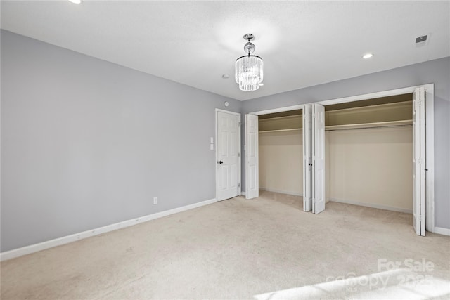 unfurnished bedroom featuring light carpet and a chandelier