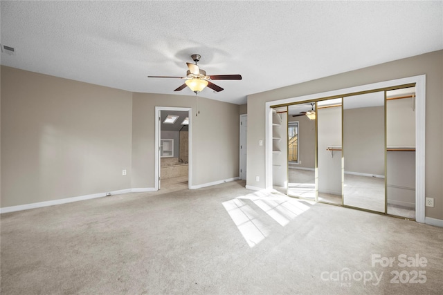 unfurnished bedroom featuring light carpet, a textured ceiling, a closet, and ceiling fan