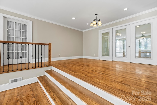 empty room with crown molding, hardwood / wood-style floors, and a notable chandelier