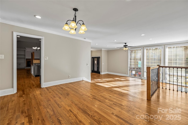 unfurnished room featuring ceiling fan with notable chandelier, ornamental molding, and hardwood / wood-style floors