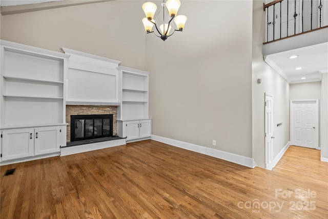 unfurnished living room featuring a towering ceiling, ornamental molding, a fireplace, and a notable chandelier