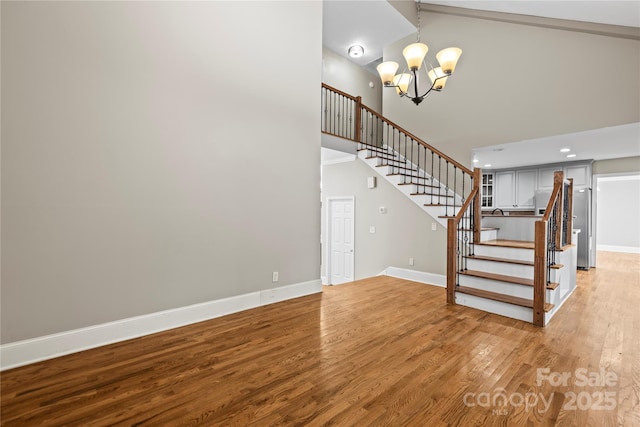 staircase with beamed ceiling, hardwood / wood-style floors, a notable chandelier, and high vaulted ceiling