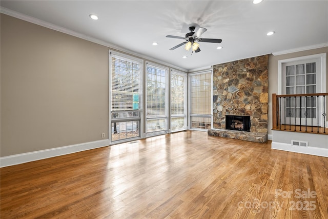 unfurnished living room featuring ornamental molding, a stone fireplace, hardwood / wood-style floors, and ceiling fan