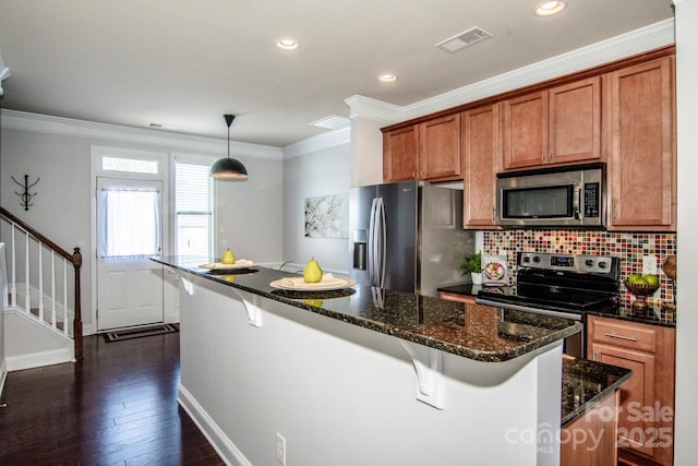 kitchen featuring a center island, stainless steel appliances, a kitchen bar, and decorative light fixtures