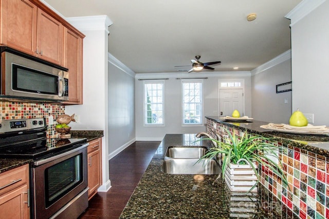 kitchen with sink, crown molding, dark stone countertops, backsplash, and stainless steel appliances