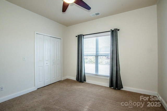 unfurnished bedroom featuring light colored carpet, ceiling fan, and a closet