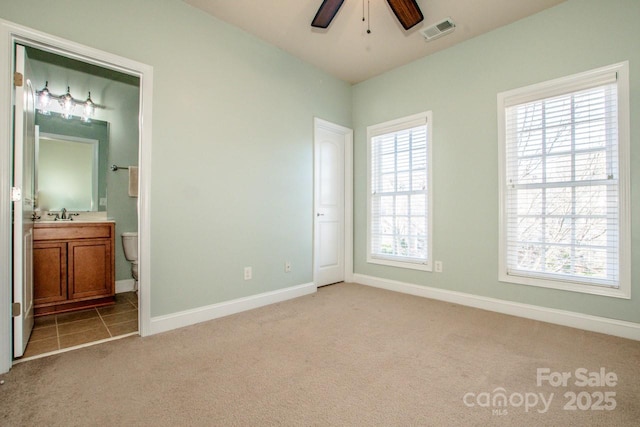 unfurnished bedroom featuring sink, light colored carpet, and ensuite bathroom