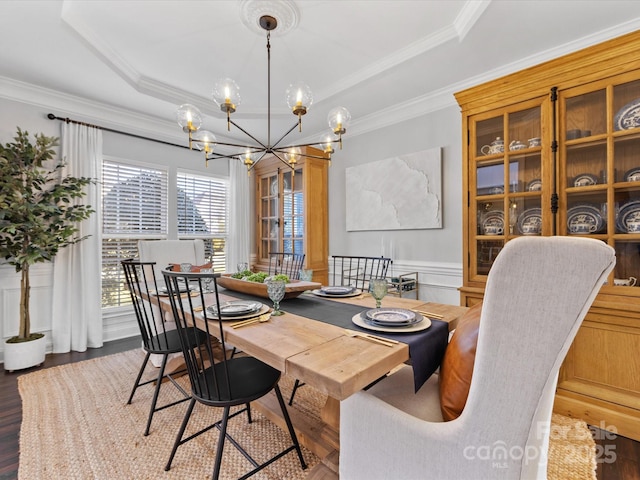 dining space featuring a notable chandelier, crown molding, wood-type flooring, and a raised ceiling