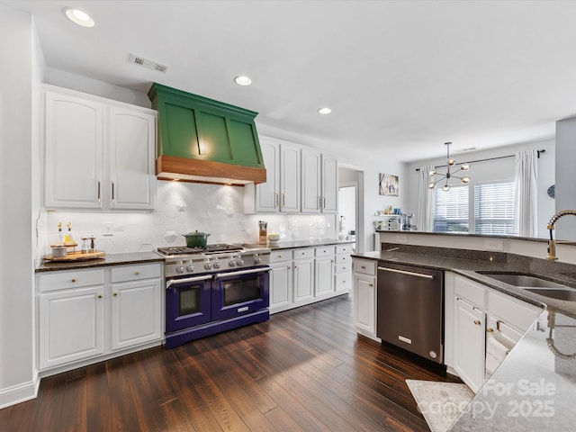 kitchen featuring appliances with stainless steel finishes, dark hardwood / wood-style floors, decorative light fixtures, sink, and white cabinets