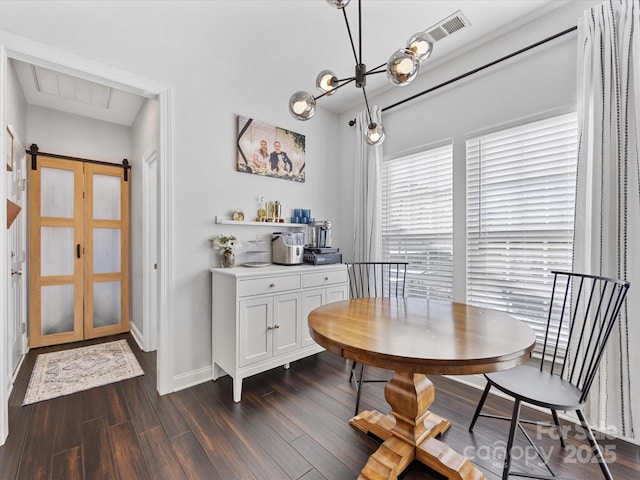 dining space with dark hardwood / wood-style flooring, a barn door, and a chandelier