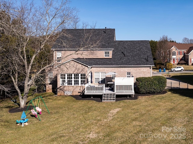 rear view of house with a lawn, a playground, and a deck