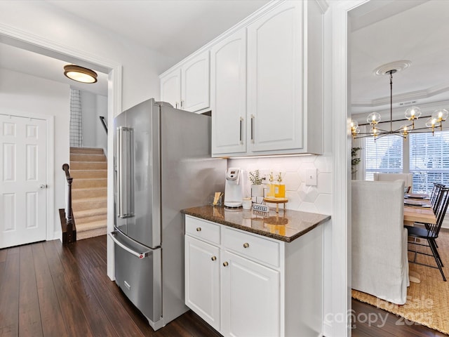 kitchen featuring high end fridge, white cabinetry, tasteful backsplash, dark stone countertops, and dark hardwood / wood-style flooring