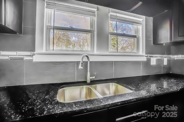 kitchen featuring sink, dark stone countertops, and backsplash