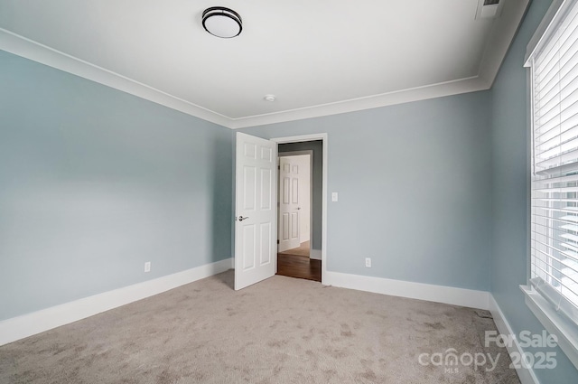 carpeted empty room featuring crown molding