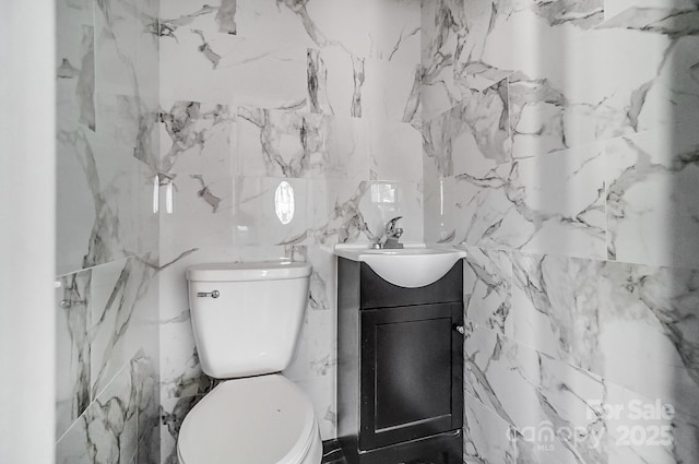 bathroom with vanity, tile walls, and toilet