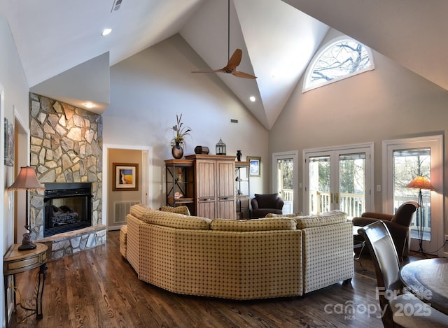 living room with a stone fireplace, high vaulted ceiling, and dark hardwood / wood-style floors