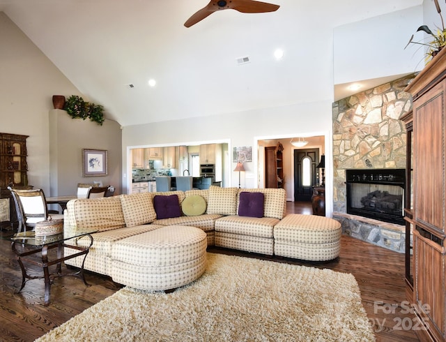 living room featuring ceiling fan, dark hardwood / wood-style floors, a fireplace, and high vaulted ceiling