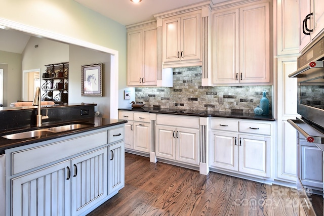 kitchen with vaulted ceiling, sink, oven, dark hardwood / wood-style flooring, and decorative backsplash