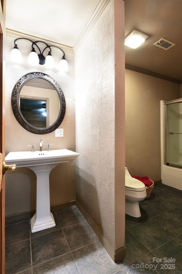 bathroom featuring ornamental molding, toilet, and a shower with door