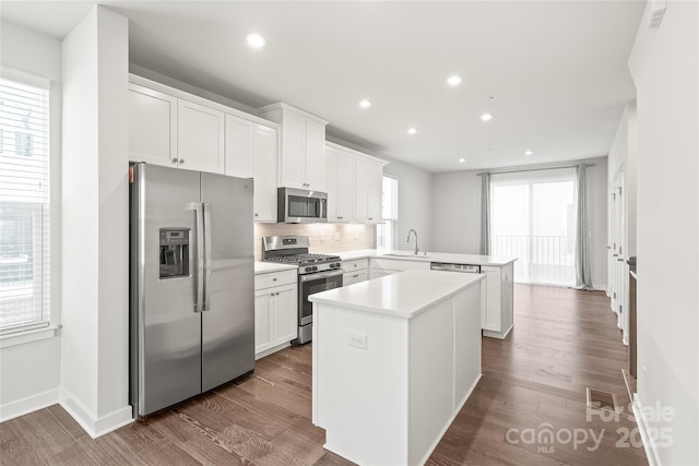 kitchen featuring a center island, white cabinetry, stainless steel appliances, sink, and kitchen peninsula