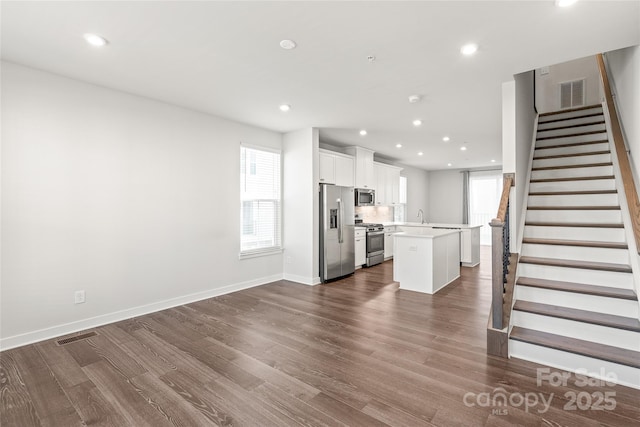 kitchen featuring dark wood-type flooring, white cabinetry, a center island, and stainless steel appliances