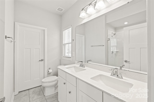 bathroom featuring vanity, toilet, tile patterned floors, and a tile shower