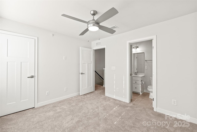 unfurnished bedroom with sink, light colored carpet, ensuite bath, and ceiling fan