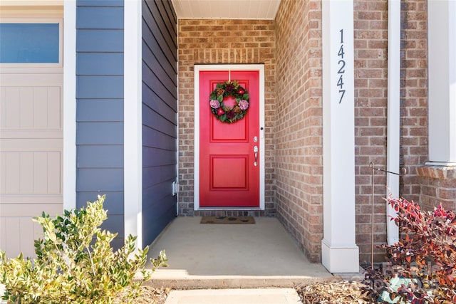 entrance to property with a garage and brick siding