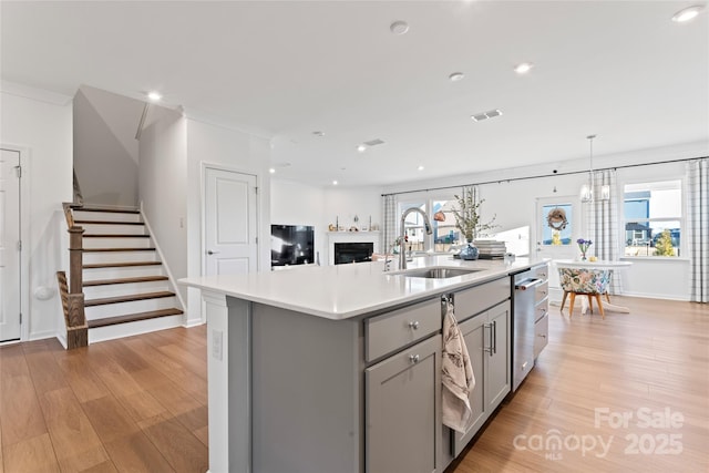 kitchen featuring light wood-style floors, light countertops, a sink, and gray cabinetry