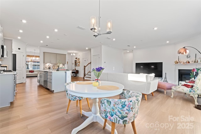 dining area with light wood finished floors, visible vents, stairs, a notable chandelier, and recessed lighting