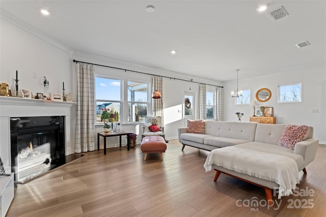 living room featuring light wood finished floors, visible vents, and crown molding