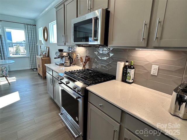 kitchen featuring stainless steel appliances, crown molding, decorative backsplash, and gray cabinetry