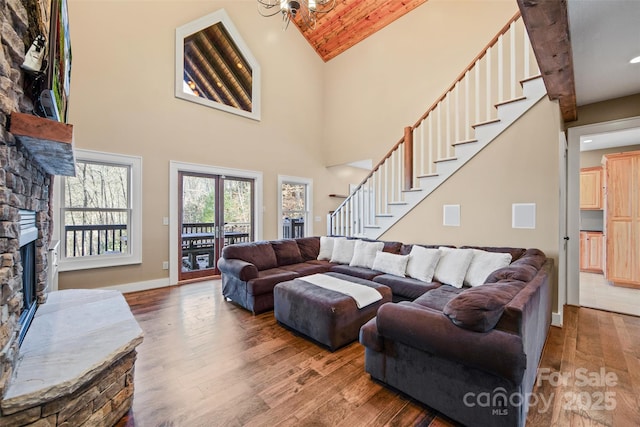 living room with hardwood / wood-style flooring, a fireplace, high vaulted ceiling, and a notable chandelier