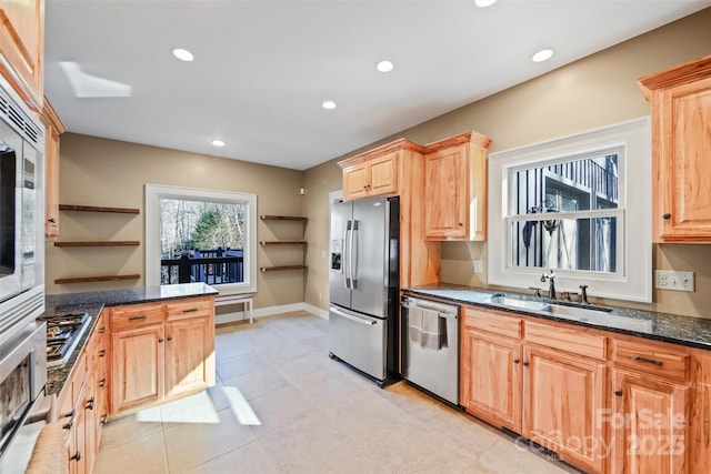 kitchen with light brown cabinetry, sink, dark stone countertops, light tile patterned floors, and stainless steel appliances