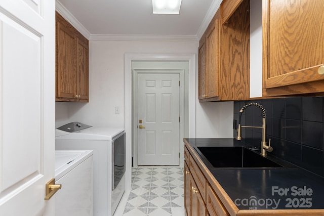 laundry room featuring cabinets, ornamental molding, separate washer and dryer, and sink