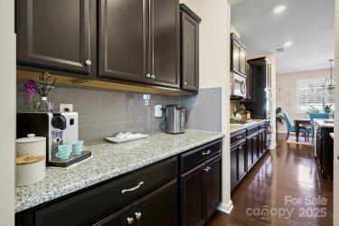 kitchen with dark hardwood / wood-style floors, dark brown cabinets, light stone countertops, and decorative backsplash