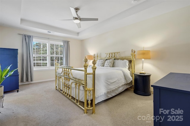 bedroom with a raised ceiling, ceiling fan, and carpet floors