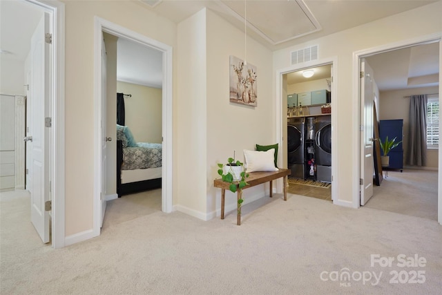 hallway featuring light carpet and washer and clothes dryer