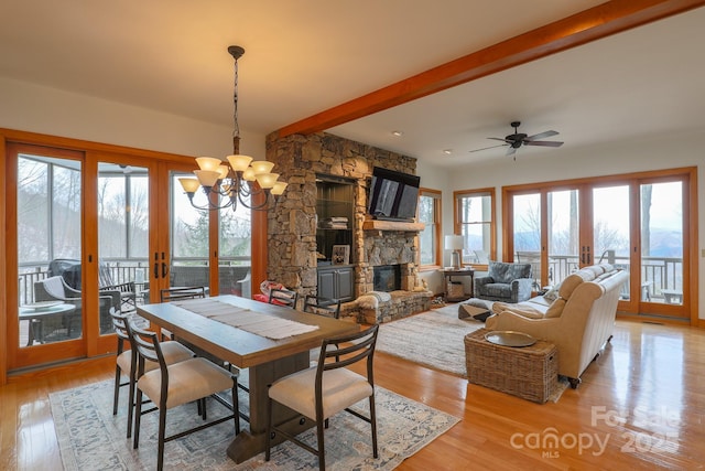 dining space with beam ceiling, a fireplace, french doors, and light wood-type flooring