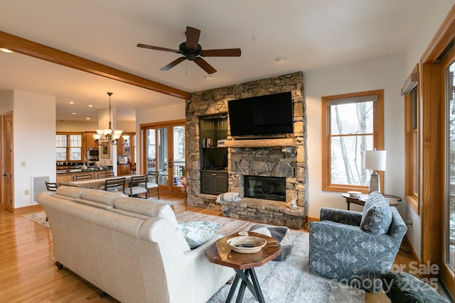 living room with beam ceiling, ceiling fan with notable chandelier, a fireplace, and light hardwood / wood-style flooring