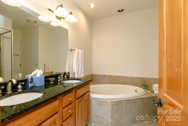 bathroom featuring a relaxing tiled tub and vanity