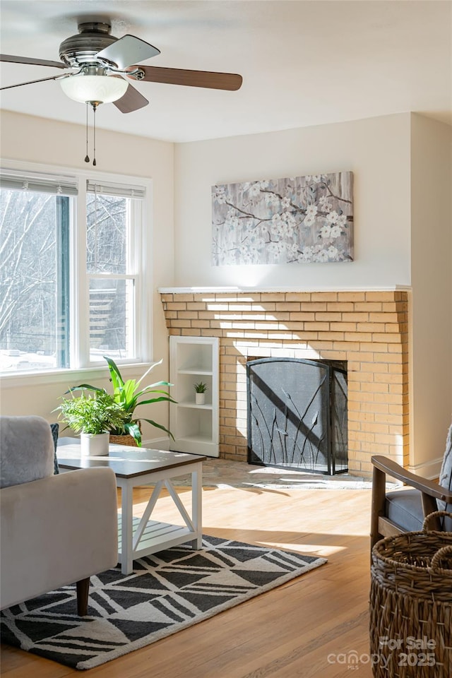 living room with hardwood / wood-style floors, a brick fireplace, and a wealth of natural light