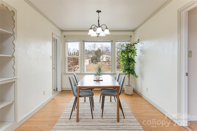 dining space featuring an inviting chandelier, crown molding, and light wood-type flooring