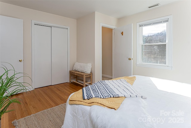 bedroom with light hardwood / wood-style floors and a closet